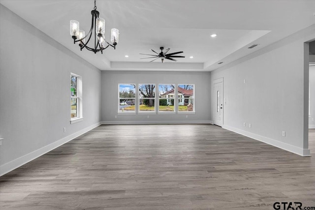 unfurnished living room with a tray ceiling, wood-type flooring, and ceiling fan with notable chandelier