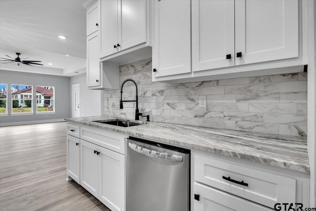 kitchen featuring stainless steel dishwasher, light stone countertops, sink, and white cabinets