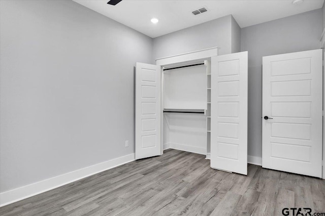 unfurnished bedroom featuring ceiling fan, light hardwood / wood-style floors, and a closet