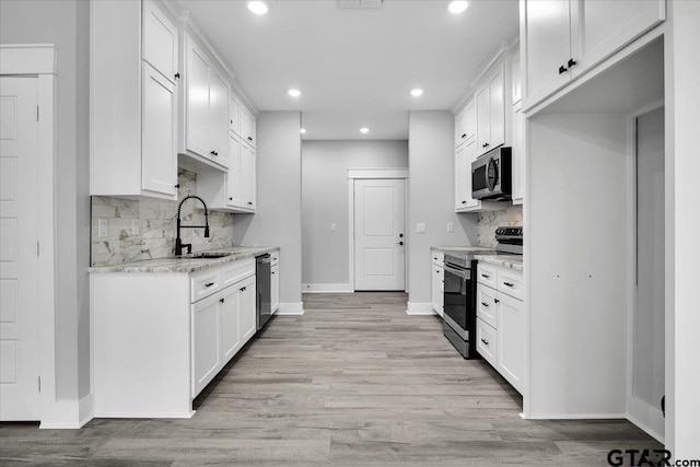 kitchen with light stone countertops, appliances with stainless steel finishes, sink, and white cabinets