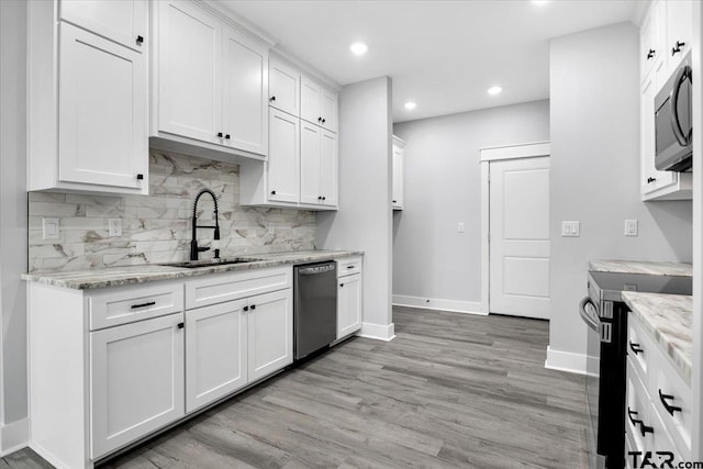 kitchen featuring white cabinetry, sink, stainless steel appliances, light stone countertops, and light wood-type flooring