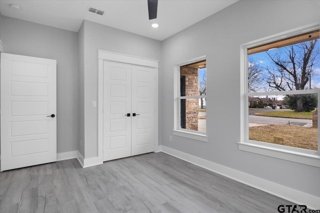 unfurnished bedroom featuring ceiling fan, a closet, and light wood-type flooring