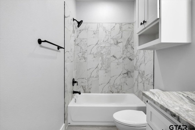 full bathroom featuring vanity, tiled shower / bath, and toilet