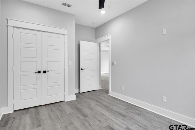 unfurnished bedroom featuring ceiling fan, a closet, and light wood-type flooring