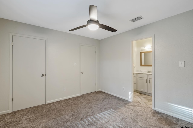 unfurnished bedroom with a closet, light carpet, ceiling fan, and connected bathroom