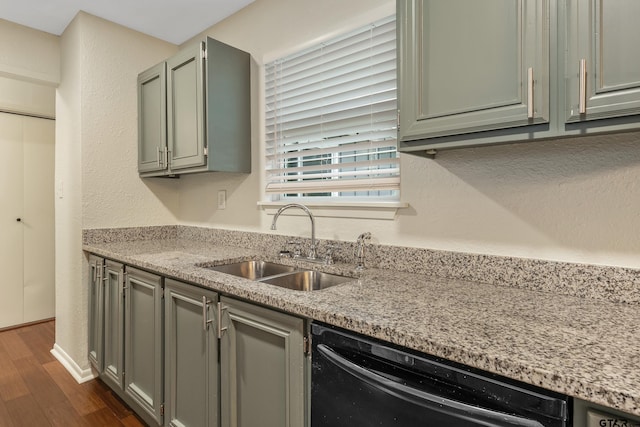 kitchen featuring dark wood-type flooring, light stone countertops, sink, and black dishwasher