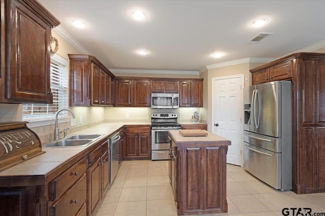 kitchen featuring light tile patterned flooring, a kitchen island, sink, ornamental molding, and stainless steel appliances