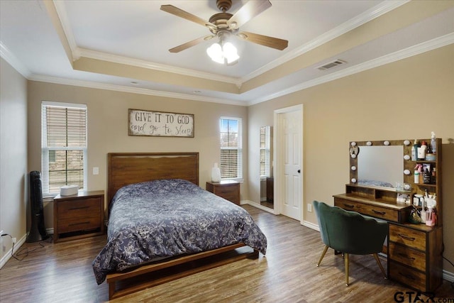 bedroom with crown molding, a raised ceiling, ceiling fan, and hardwood / wood-style flooring