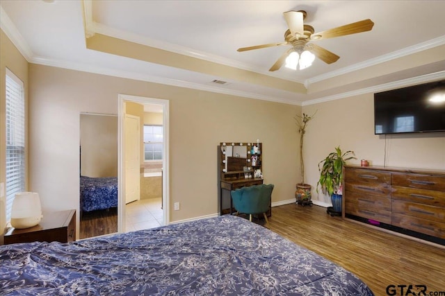 bedroom with ceiling fan, crown molding, ensuite bath, and a tray ceiling