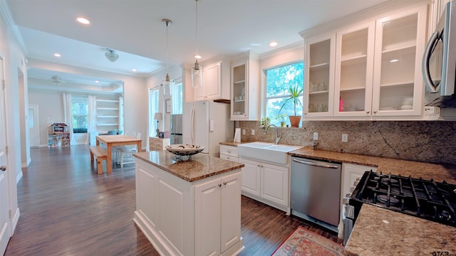 kitchen with a sink, stainless steel appliances, white cabinetry, decorative backsplash, and dark wood-type flooring