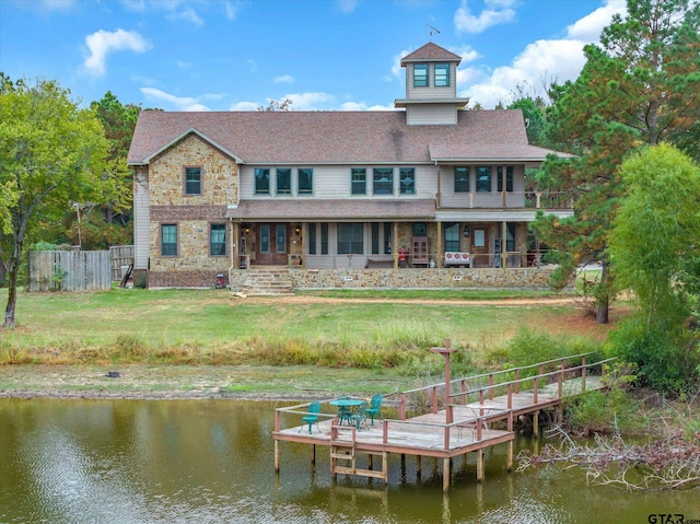 rear view of property featuring a lawn and a water view