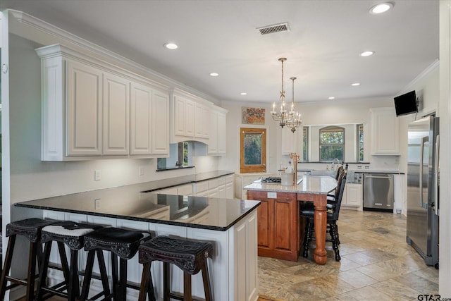 kitchen featuring white cabinets, a center island, kitchen peninsula, and stainless steel appliances