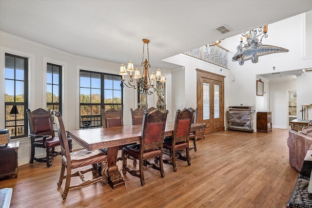 dining area with a notable chandelier, light wood-type flooring, crown molding, and french doors