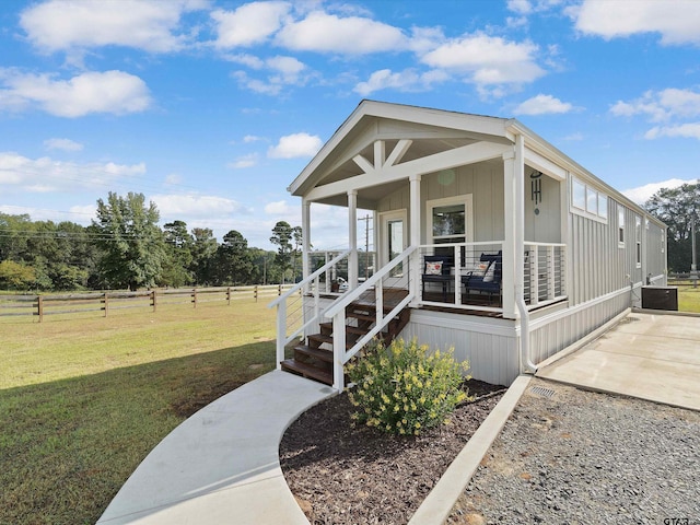 view of front of property featuring covered porch, a front yard, and a rural view