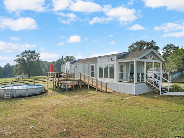 rear view of house with a pool side deck, a sunroom, and a lawn