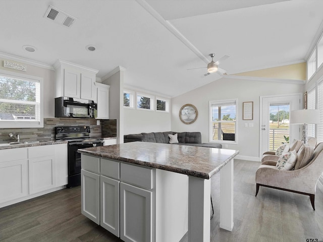 kitchen featuring white cabinetry, decorative backsplash, a center island, black appliances, and dark wood-type flooring