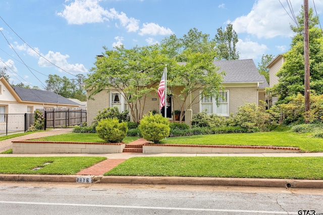 view of front facade with brick siding, fence, and a front yard
