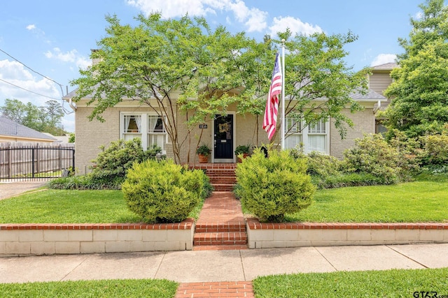 view of front of home with brick siding, fence, and a front yard