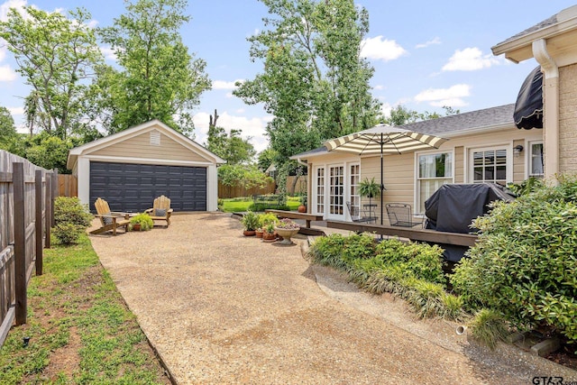 view of yard featuring a detached garage, fence, an outdoor structure, and french doors