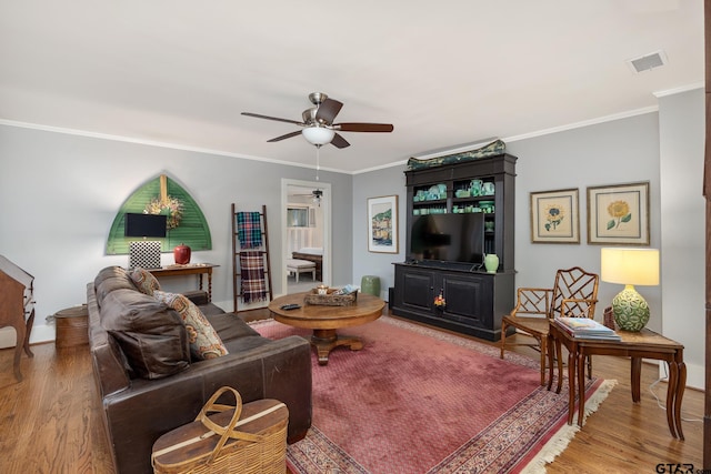 living room featuring crown molding, a ceiling fan, baseboards, and wood finished floors