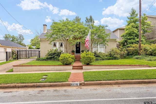 view of front of property featuring fence, a front yard, roof with shingles, a chimney, and brick siding