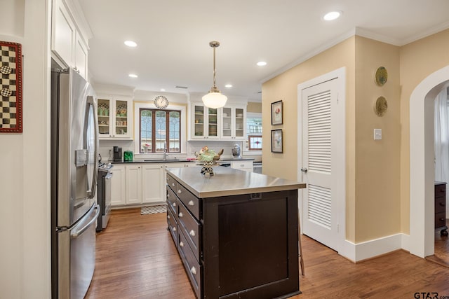 kitchen with crown molding, arched walkways, a sink, white cabinets, and stainless steel appliances