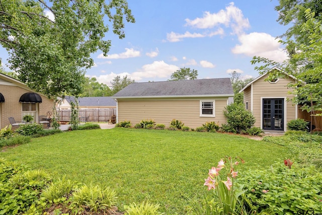 view of yard featuring fence and french doors