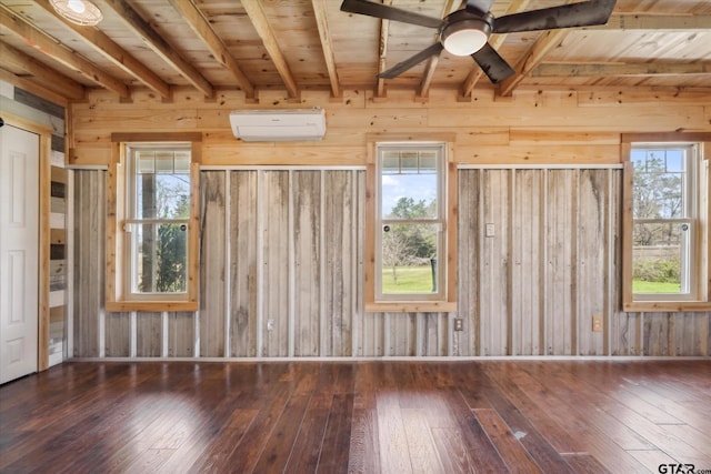 spare room with a wall mounted AC, ceiling fan, beamed ceiling, and hardwood / wood-style flooring