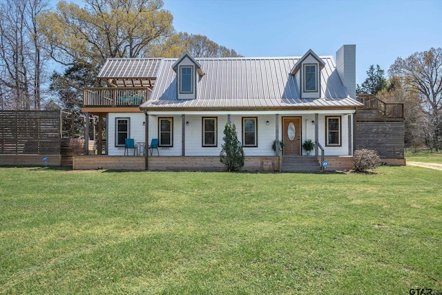 view of front of property featuring metal roof, a chimney, a front lawn, and a porch