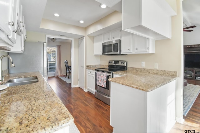 kitchen with light stone counters, a sink, stainless steel appliances, dark wood-type flooring, and white cabinets