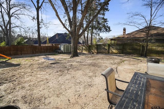 view of yard featuring a storage shed, a fenced backyard, and an outdoor structure