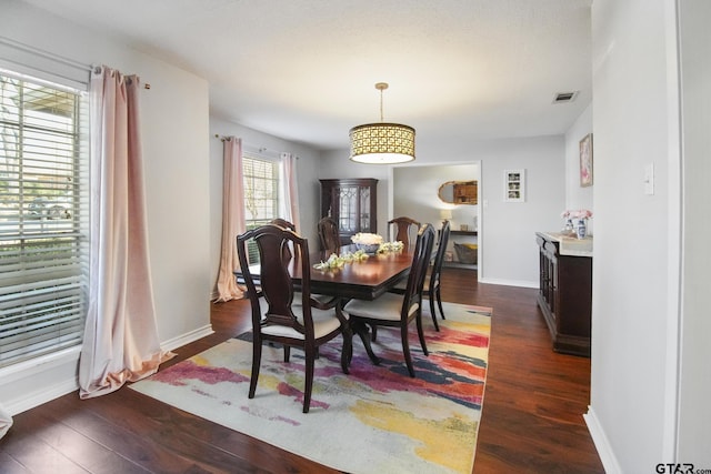 dining space featuring visible vents, baseboards, and dark wood finished floors