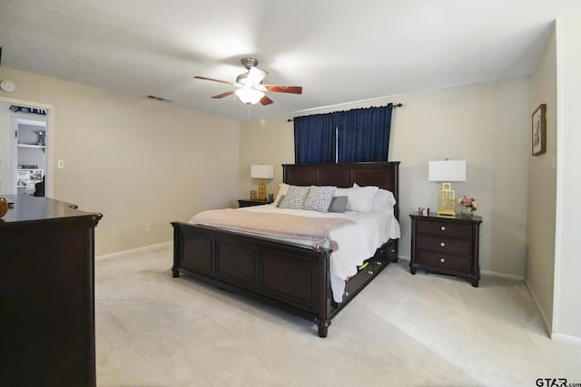 bedroom with visible vents, light colored carpet, baseboards, and ceiling fan