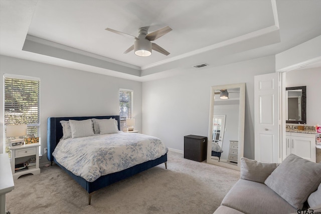 bedroom featuring a raised ceiling, multiple windows, and ceiling fan