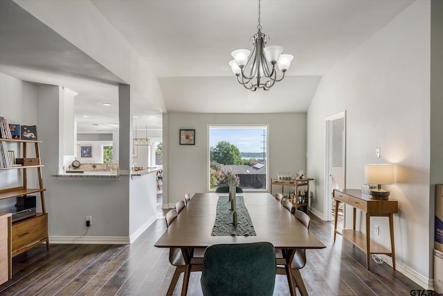 dining area with dark hardwood / wood-style flooring, lofted ceiling, and an inviting chandelier