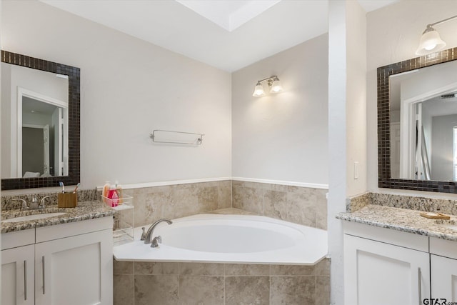 bathroom featuring tiled bath and vanity