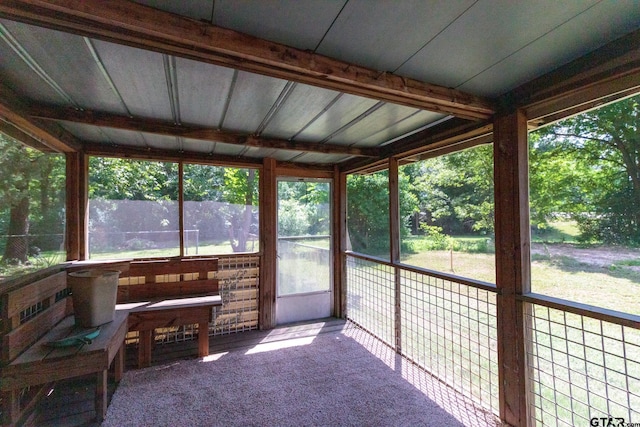 unfurnished sunroom featuring beam ceiling and a healthy amount of sunlight