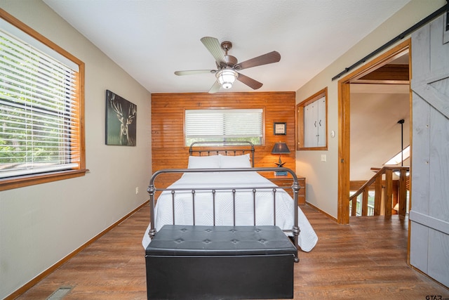203 King Laurence Ct, Scroggins, TX 75480 - bedroom with multiple windows, wood walls, wood finished floors, baseboards, and ceiling fan