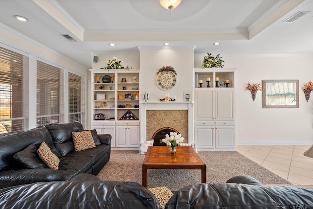 living area with a raised ceiling, light tile patterned floors, visible vents, and ornamental molding