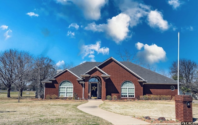 single story home with brick siding, a shingled roof, and a front yard