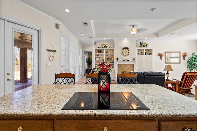 kitchen with crown molding, black electric stovetop, open floor plan, and a tray ceiling