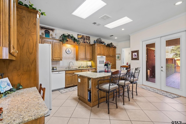 kitchen featuring visible vents, a sink, a kitchen breakfast bar, french doors, and white appliances