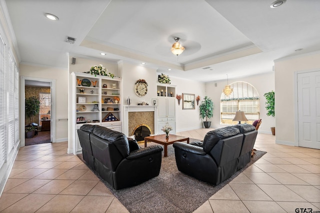 living area featuring light tile patterned floors, visible vents, crown molding, and a tray ceiling