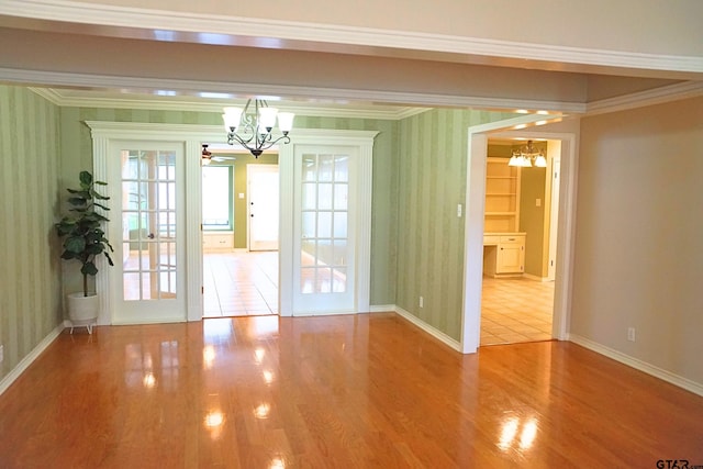 interior space with an inviting chandelier, ornamental molding, and hardwood / wood-style floors