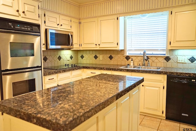 kitchen with tasteful backsplash, black appliances, sink, light tile patterned flooring, and dark stone counters