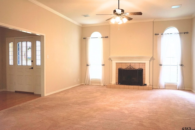 unfurnished living room with ceiling fan, carpet, a tile fireplace, and crown molding