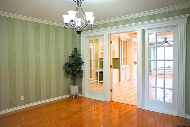 entryway with a chandelier, crown molding, and wood-type flooring