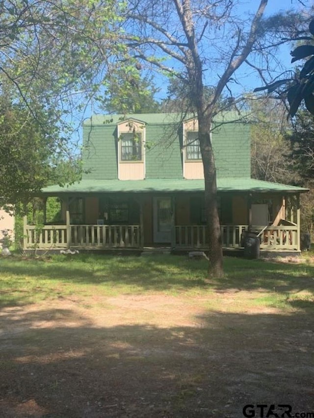 farmhouse inspired home with covered porch and a front lawn