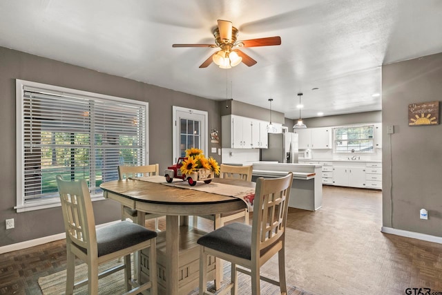 dining room with dark parquet flooring, a wealth of natural light, and ceiling fan