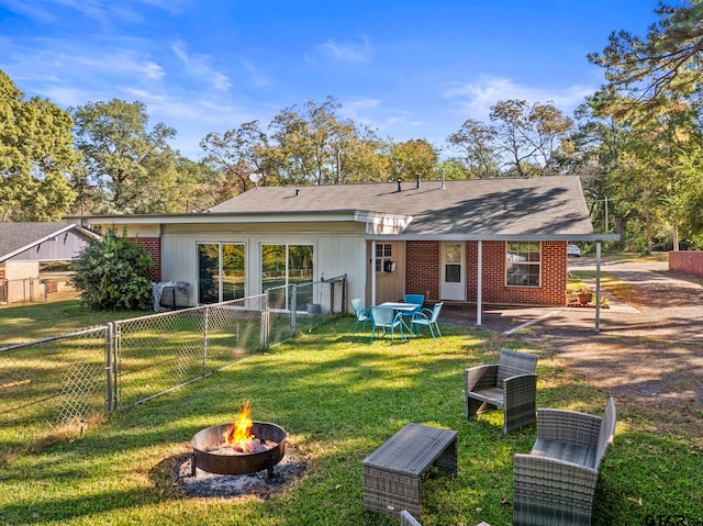 rear view of property featuring an outdoor fire pit, a patio, and a yard